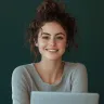 Smiling young woman with her hair tied up, sitting at a laptop