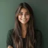 Smiling young woman with long dark hair in front of a green wall